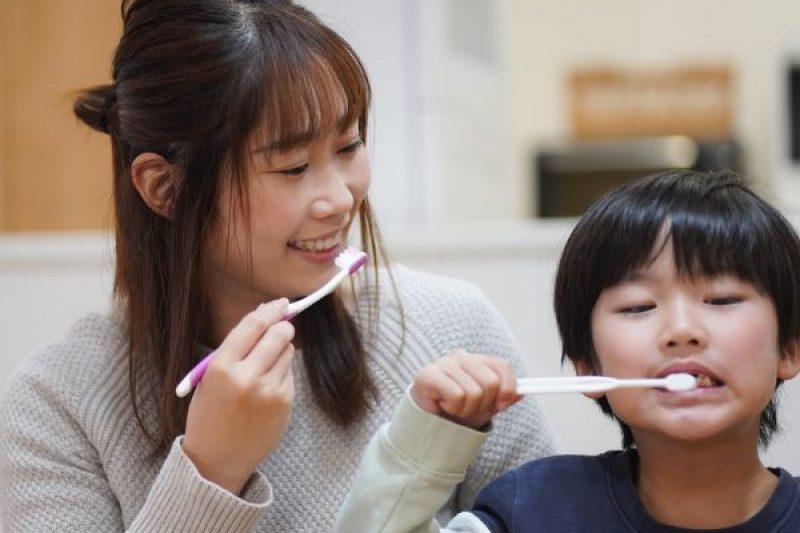 Kid Brushing Teeth with Mom